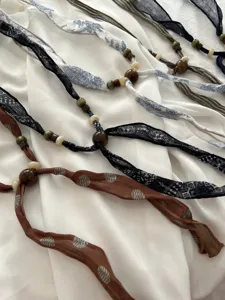 Detailed view of retro fabric ribbon necklaces with wooden beads and linen material charms.