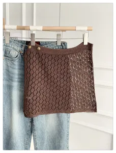 Detailed view of brown hollow knit skirt with button decor, stylish layering piece.