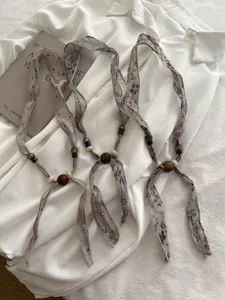 Vintage stoffen houten kralen lint sjaal ketting detailopname, elegant minimalistisch