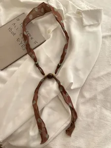 Vintage fabric scarf necklace with wooden beads, elegant brown ribbon for spring outfits.