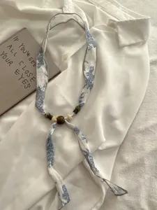 Detail shot of retro linen ribbon scarf necklace with wooden beads, elegant fashion accessory.