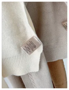 Knitted shawl fabric detail view, soft wool blend texture and material label close-up.