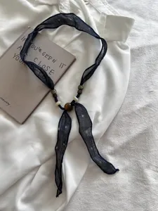 Retro artistieke stoffen houten kraal sjaal ketting detail, elegant zwart mesh lint.