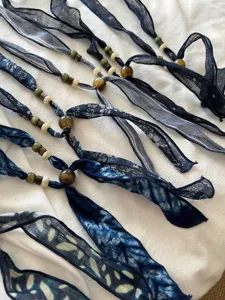 Detailopname van de blauwe batik stoffen lint halsketting met vintage kralen in literaire stijl.