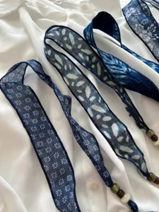 Gedetailleerde close-up van blauw tie-dye linnen kralenlint met fijne bedrukte bloemmotieven.