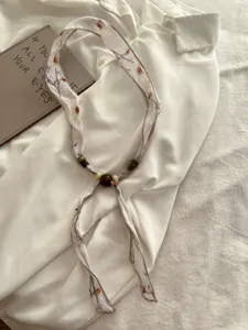 Gedetailleerd overzicht van linnen kralensjaal met bloemenprint, elegante halsaccessoire.