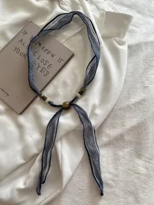Detail van de linnen kraal lint ketting, blauwe tie-dye stof sjaal halsketting.