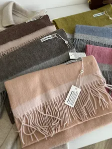 Close-up detail of luxurious 100% wool dual-color fringe scarf texture and tags.