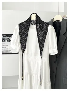 Black crochet knit triangle scarf with bead detail styled over white dress detail view.