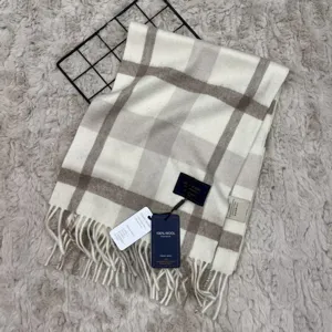 Close-up detail of winter wool plaid scarf with fringes, showing soft texture and woven tags.