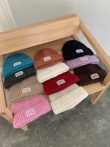 Detailed shot of colorful knitted beanies showcasing soft texture and cute woven labels.