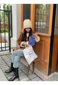 Cozy autumn winter knitted beanie hat styled with chic casual daily outfit in outdoor street scene.