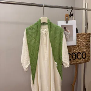 Primo piano dettagliato dello scialle sciarpa triangolare in maglia traforata verde.