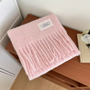Detailed view of fluffy pink winter scarf with fringe, cozy texture and delicate lace patch.