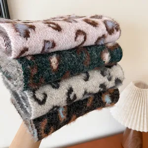 Detailed view of cozy fuzzy leopard print winter scarves stacked neatly with warm fabric texture.