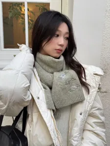 Close-up detail of the cozy wool blend knitted scarf featuring cute embroidered sheep patterns.