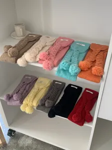 Detail view showing assorted colorful winter knit scarves with cute pom poms for women.