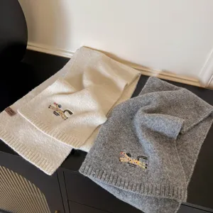 Detailed close-up view of the cozy winter knit scarves featuring cute embroidered horse motifs.