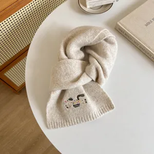 Detail shot of a cozy beige wool blend scarf featuring cute embroidered horse motif and texture.