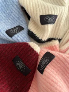 Close-up detail of soft wool blend knit scarves in various colors with brand label.