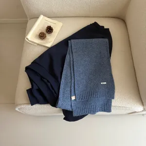 Detailed view of the cozy blue knitted scarf styled with a dark top and rustic book props.