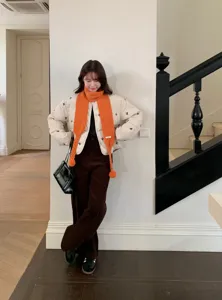 Stylish women winter solid color knit pom pom scarf with cozy puffer jacket outfit.