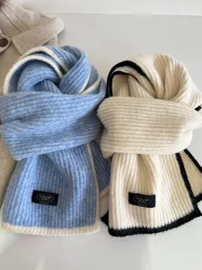 Detailed shot of soft knit wool winter scarves with contrasting edge design and brand label.