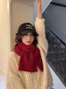 Detailed lifestyle close-up showing the warm red wool scarf and black embroidered baseball cap.
