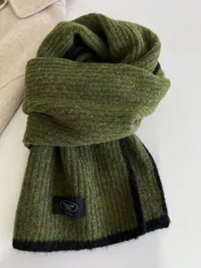 Knitted wool scarf with contrast black edge, soft texture, cozy winter accessory detail.