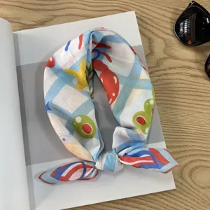 Detail view of blue and white checkered cotton square scarf featuring colorful playful cartoon prints.