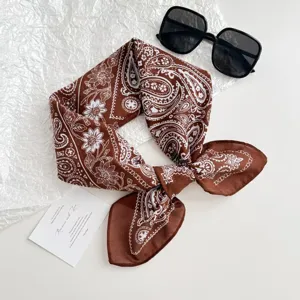 Detail shot of brown paisley cotton-linen feel square scarf with sunglasses prop.
