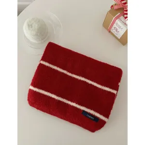 Roter Strickschal mit weißen Streifen im Detail, gemütliches Winteraccessoire, weich und warm.