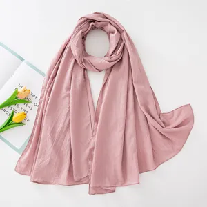 Dettaglio della sciarpa hijab rosa spiegazzata, mostra consistenza traspirante e tessuto.