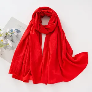 Dettaglio di sciarpa lunga plissettata rossa in viscosa con trama fine e drappeggio.