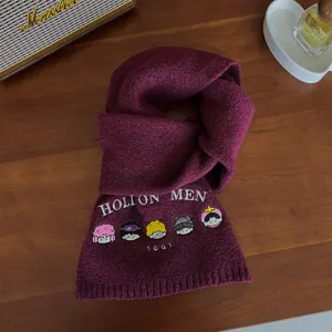 Close-up detail of warm burgundy knit wool scarf with cute cartoon character embroidery.