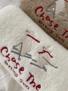 Close-up detail of winter cozy embroidered skiing bear pattern warm plush scarf fabric.