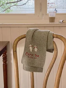 Detailed view of cozy gray winter knitted scarf featuring cute ski bear embroidery and english text.