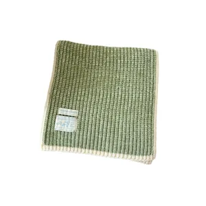 Green knitted winter scarf for women, soft wool blend cozy neck warmer with stylish labels.