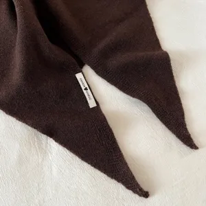 Detailweergave van een donkerbruine wollen gebreide driehoekige sjaal voor de winter.