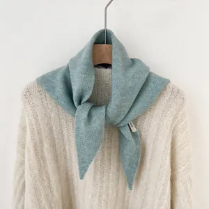 Close-up detail van een zachte blauwgroene gebreide driehoekige sjaal, warme winternekwarmer.