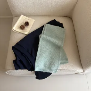 Knit scarf and dark blue top detail shot displaying soft texture and cozy winter style.