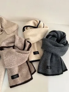 Knit wool scarf detail showing soft texture, piped edges, and stylish winter neck warmer design.