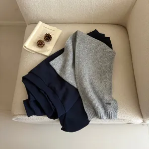 Detailed view of the cozy grey knitted scarf styled on soft fabric for winter wear.