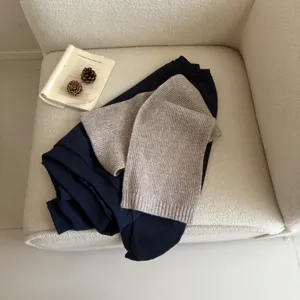 Detail shot of cozy knit scarf paired with navy sweatshirt, showing soft wool texture and elegant drape.
