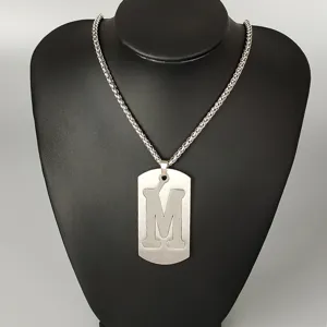 Stainless steel letter M pendant necklace detail view, fashion hip hop street style jewelry item.
