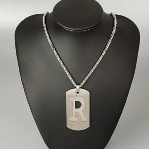 Stainless steel letter R pendant necklace detail view, hip hop street style jewelry close up.