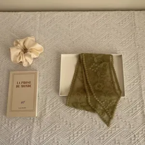 Detail shot of retro green floral lace ribbon scarf, vintage aesthetic flat lay photography.