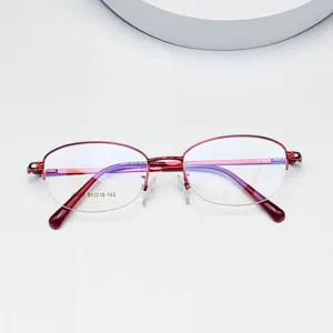 Detailed close-up of red metal half-frame optical glasses, stylish oval design for women.