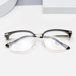 Close-up detail of stylish half-frame glasses with black and gold design, clear lenses.
