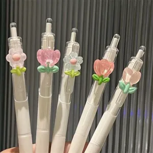 Primer plano de bonitos bolígrafos de gel florales con dijes de flores de resina transparente.